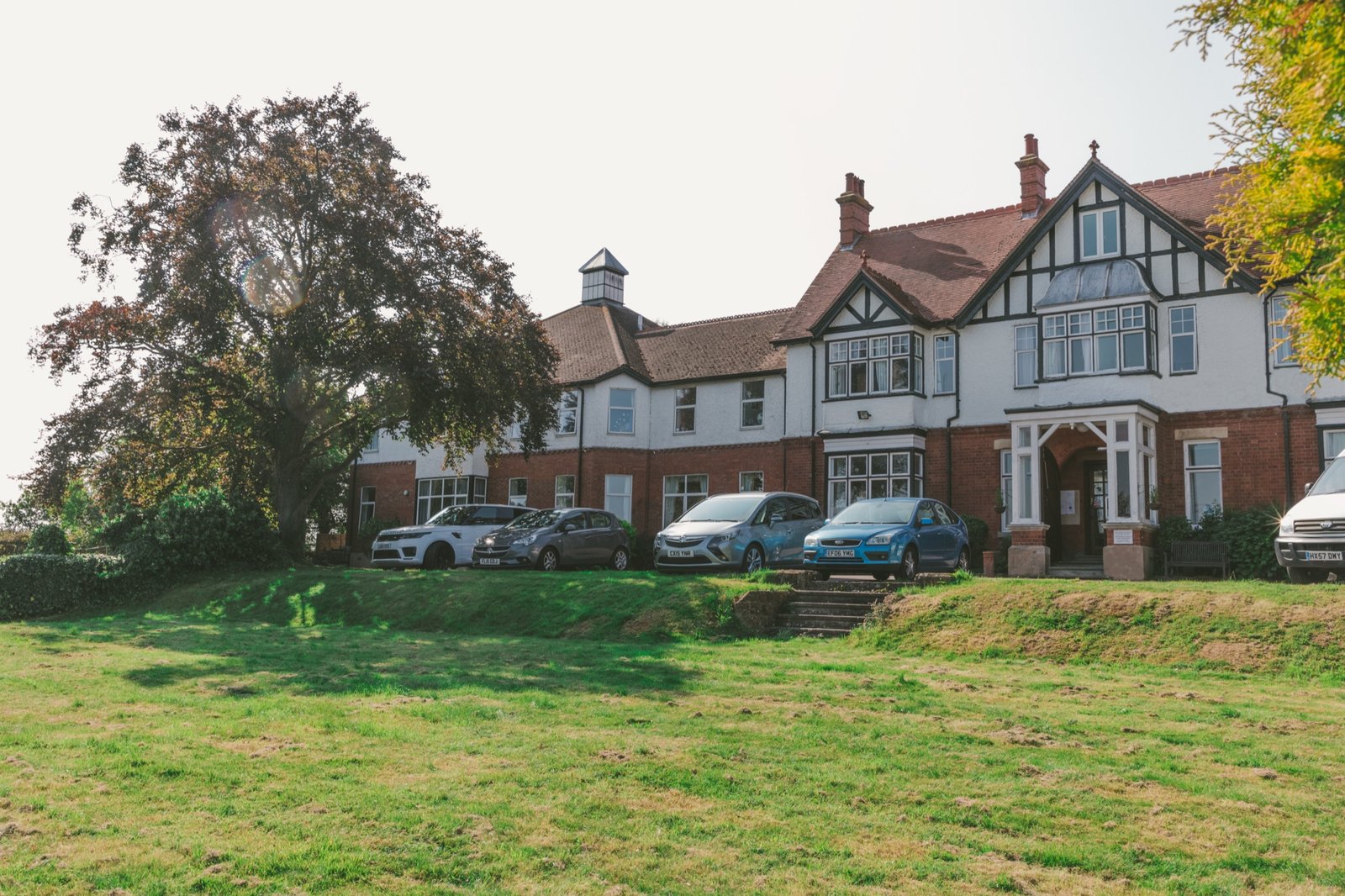 The warm, tree-lined exterior of a care home, photographed in soft afternoon light